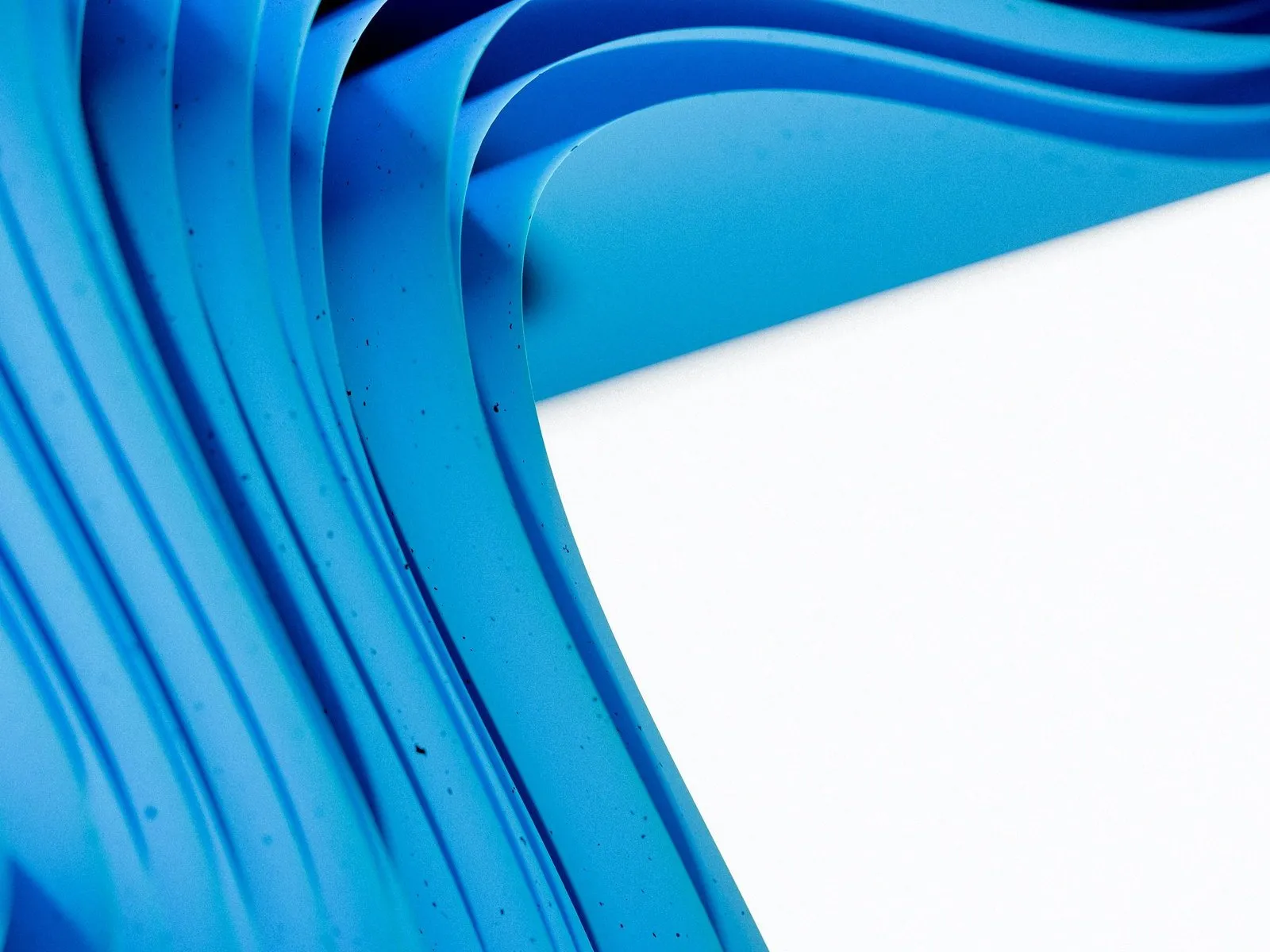 Layered sheets of blue paper curving in waves beside a clean white surface